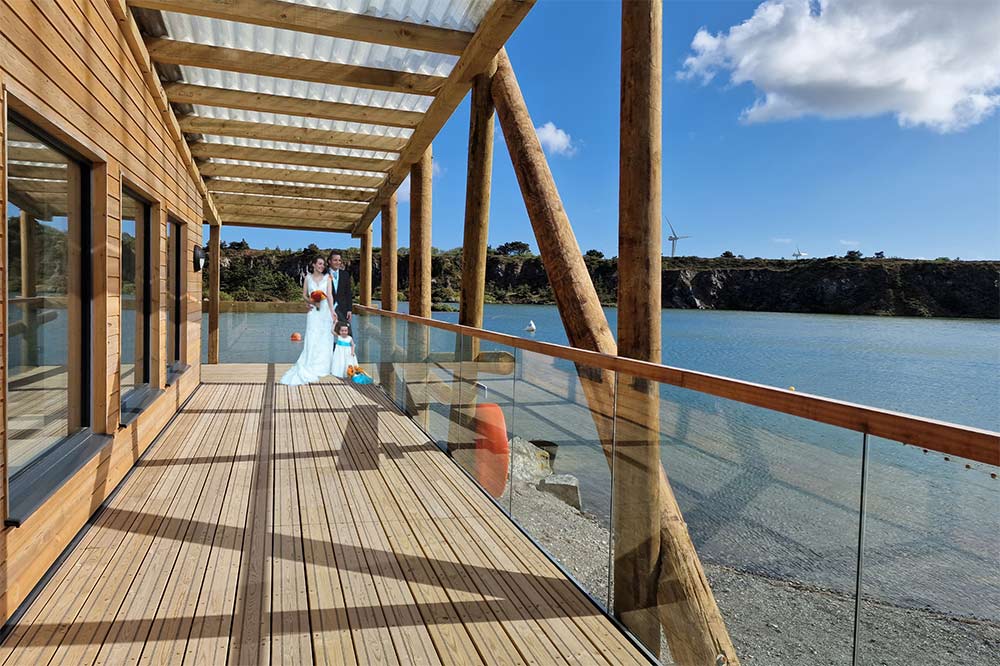 Wedding couple standin gon the lakeside deck at Trevassack